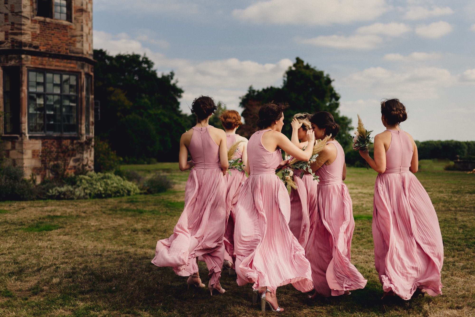bridesmaids walking to the ceremony in the wind at Dorfold Hall