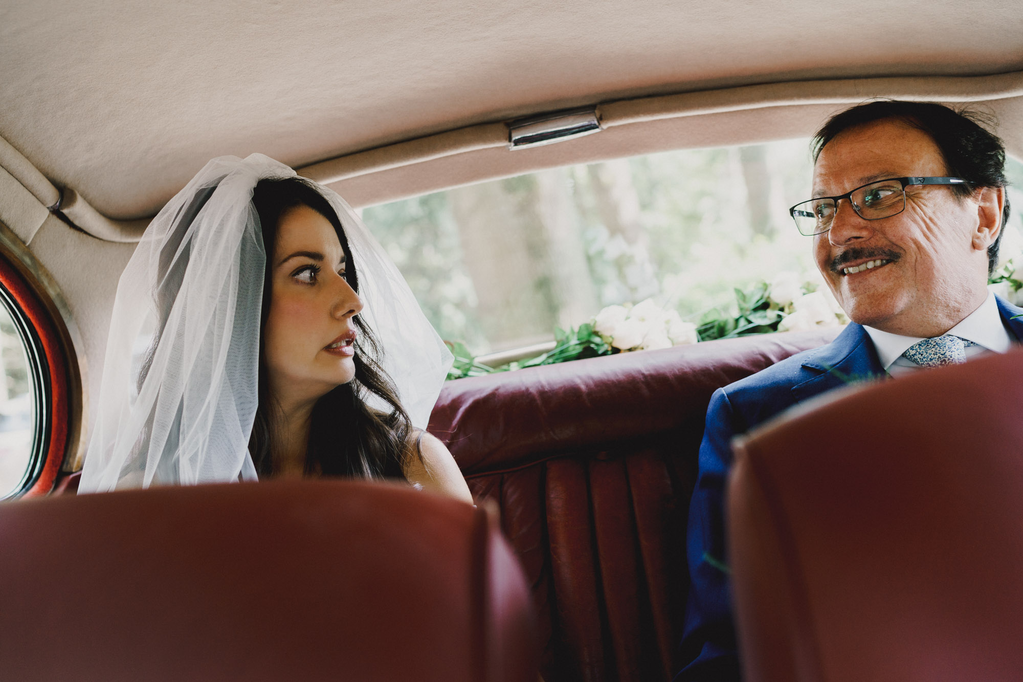 documentary image of bride looking at dad in a worried manor in the car on the way to the ceremony